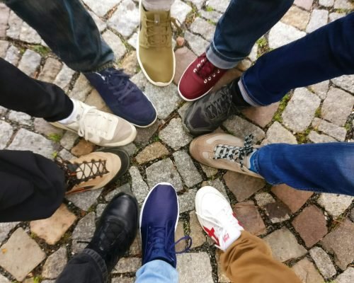 Circle of sneakers on cobblestone pavement representing diversity and urban fashion.